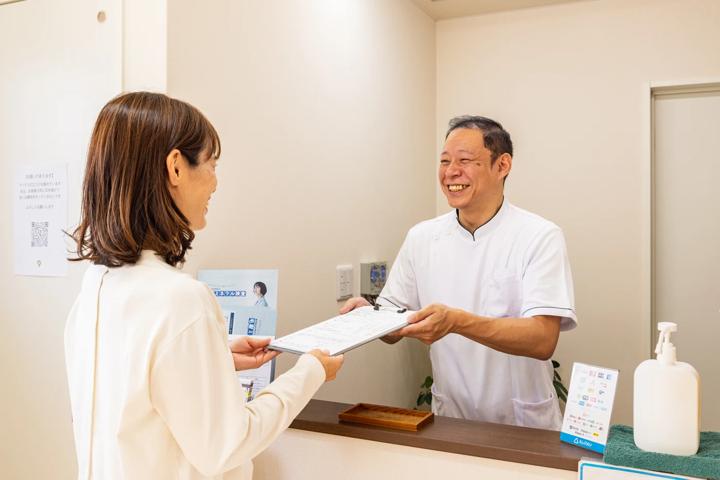 院長が受付で来院された方をご案内する様子